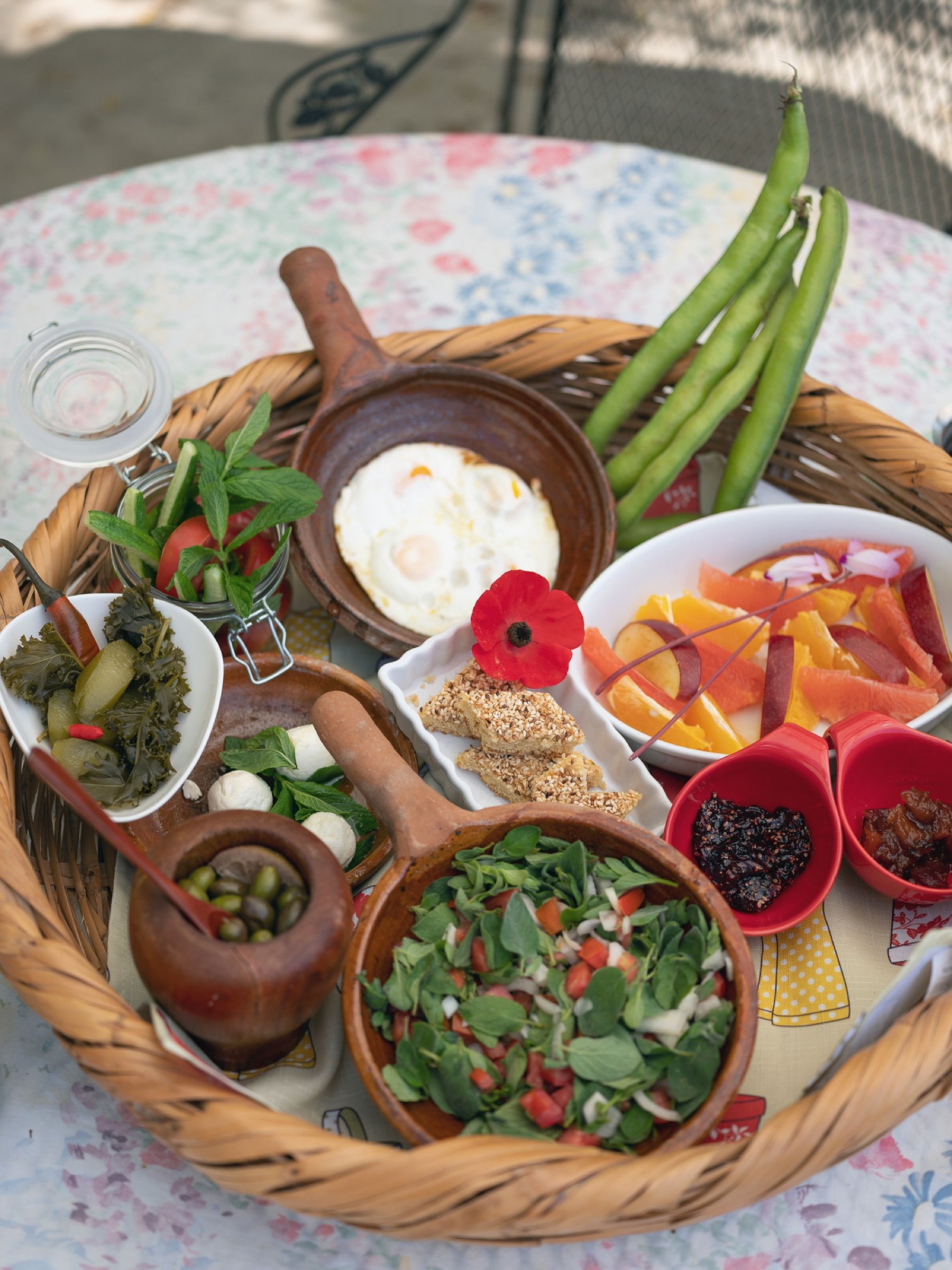 A woven tray of mezze — labneh, salad, olives, radishes and flatbread — laid out on a painted table