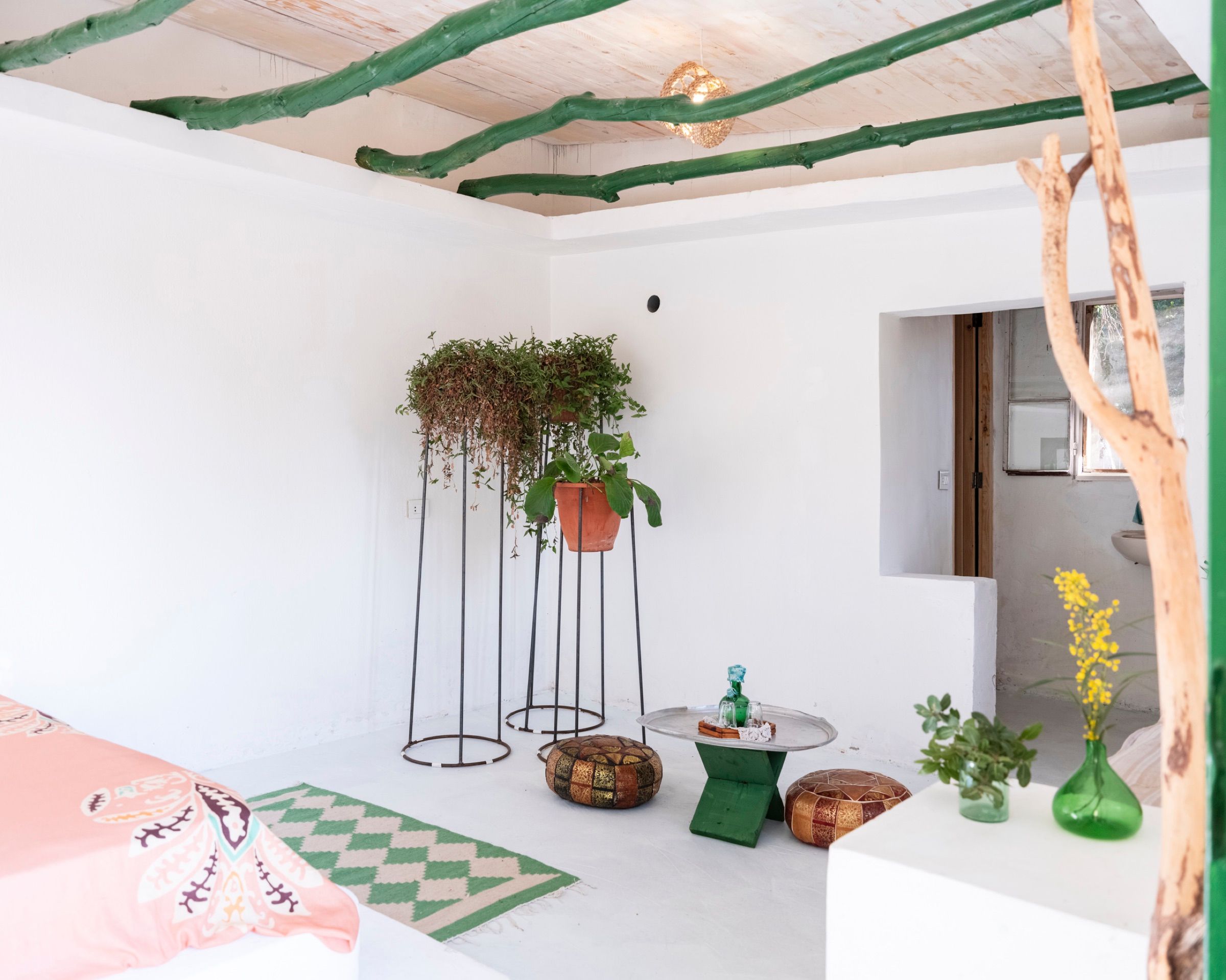 The Thyme room, with green-painted ceiling beams, hanging plants in woven baskets and a bed dressed in pink